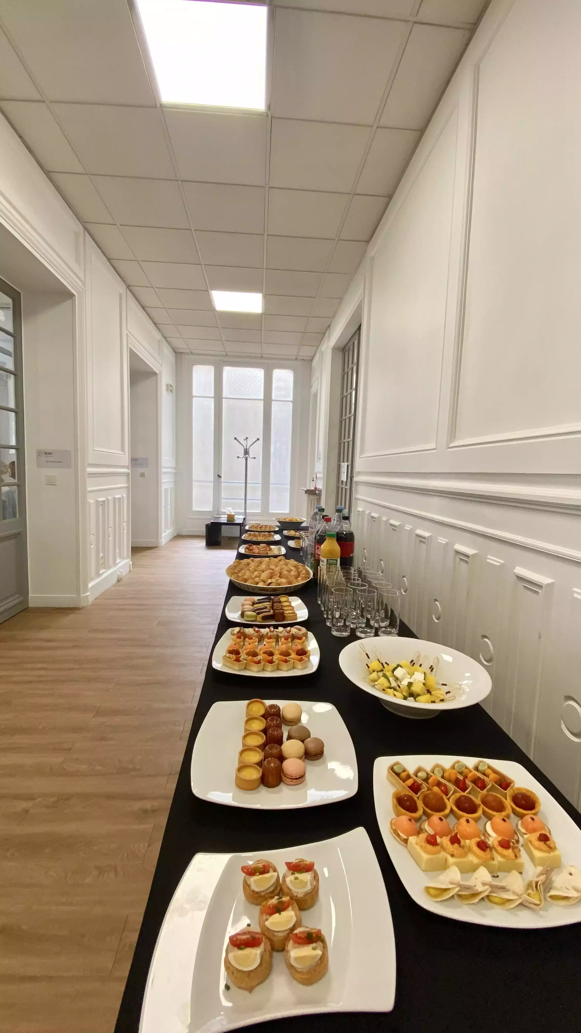 Couloir éclairé avec un buffet de finger foods sur assiettes blanches