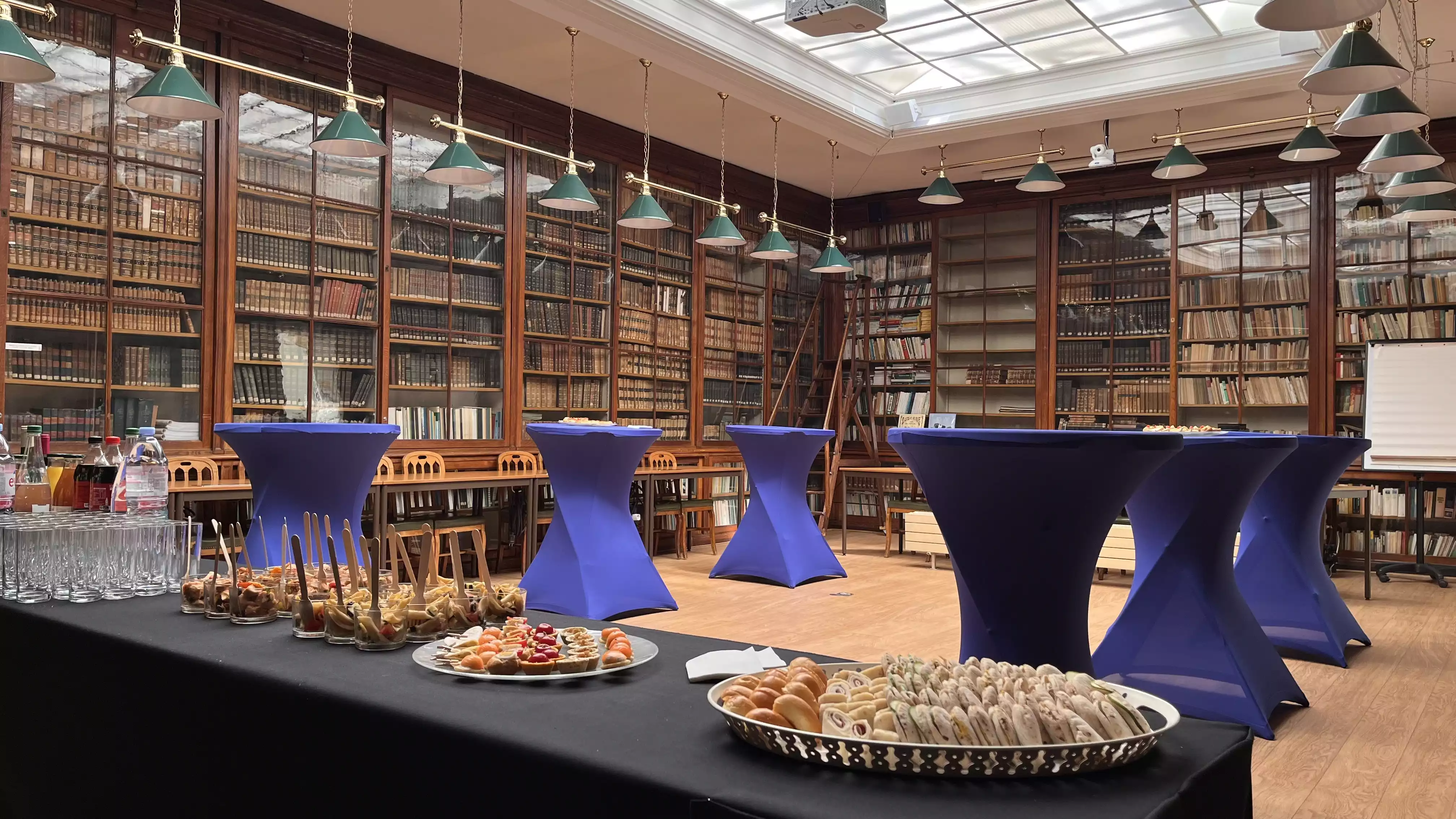 Traiteur élégant dans une bibliothèque avec étagères en bois et lampes suspendues vertes